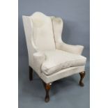 A late 19th century wing armchair in the George II style, with out-swept arms, raised on walnut