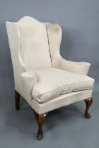 A late 19th century wing armchair in the George II style, with out-swept arms, raised on walnut