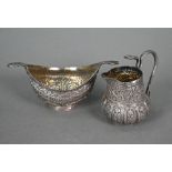 An Indian low-grade silver small cream and sugar pair with cobras' heads handles and foliate