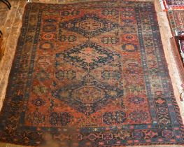 An antique Caucasian Sumak / Soumak carpet, the brown-red ground with geometric guls within wide