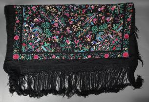 A Chinese black silk fringed piano shawl, abundantly embroidered with Pagoda scenes, figures and