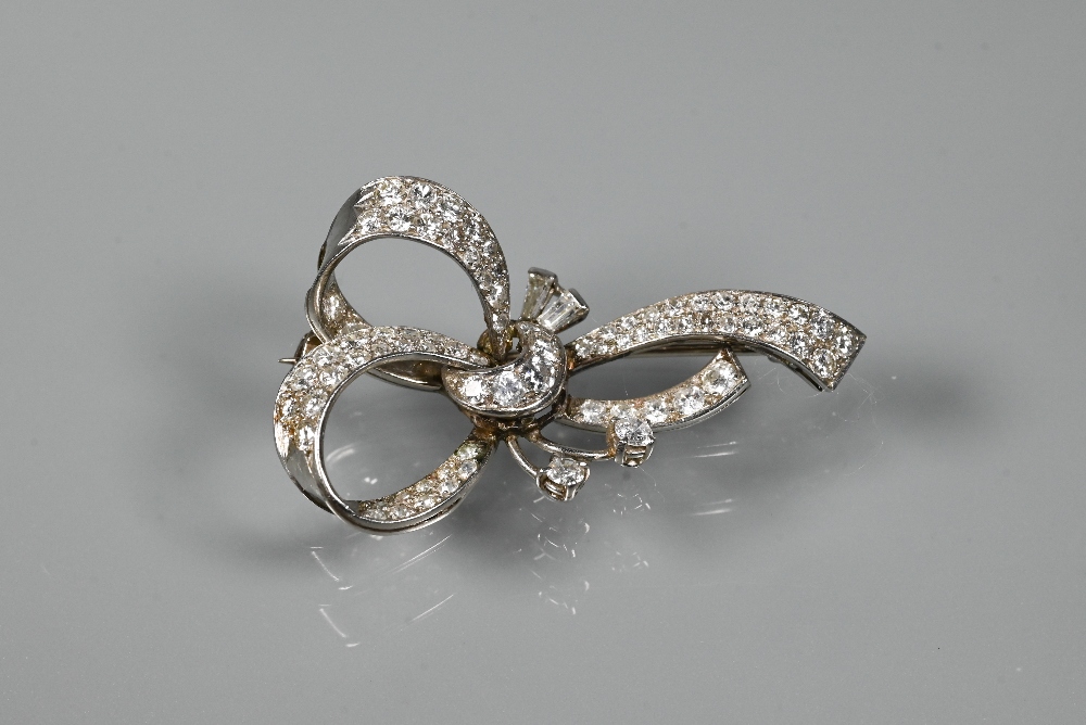 A diamond brooch, the white metal set overall with mixed cut diamonds in the style of a loosely-tied