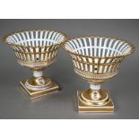 A pair of Continental porcelain pierced baskets with flared tops and stemmed square bases, decorated