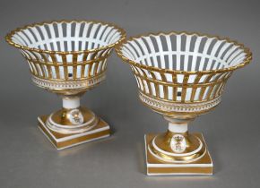 A pair of Continental porcelain pierced baskets with flared tops and stemmed square bases, decorated