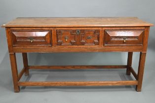 An 18th century style three drawer low dresser, the centre drawer with applied geometric