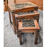 A trio of Indian hardwood nest of tables with iron grilled top under glass, the largest 44.5 x 30