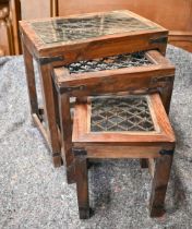 A trio of Indian hardwood nest of tables with iron grilled top under glass, the largest 44.5 x 30