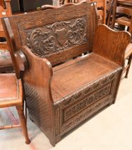 An oak monk's bench carved with armorials and foliate decoration, 90 cm wide