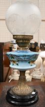 An antique ceramic and brass oil lamp with etched glass shade