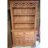 A waxed pine dresser with plate rack on a base with two drawers and quad-panelled doors, 118 cm wide