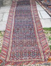 An old Caucasian runner with repeating diamond medallions on navy field, and multi-coloured