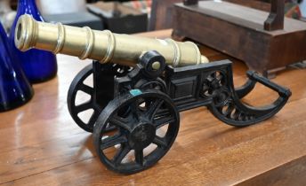 WITHDRAWN A brass model cannon on cast iron stand, 46 cm long