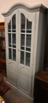 A distress-grey painted French dresser with part-glazed and arch panelled doors enclosing shelves