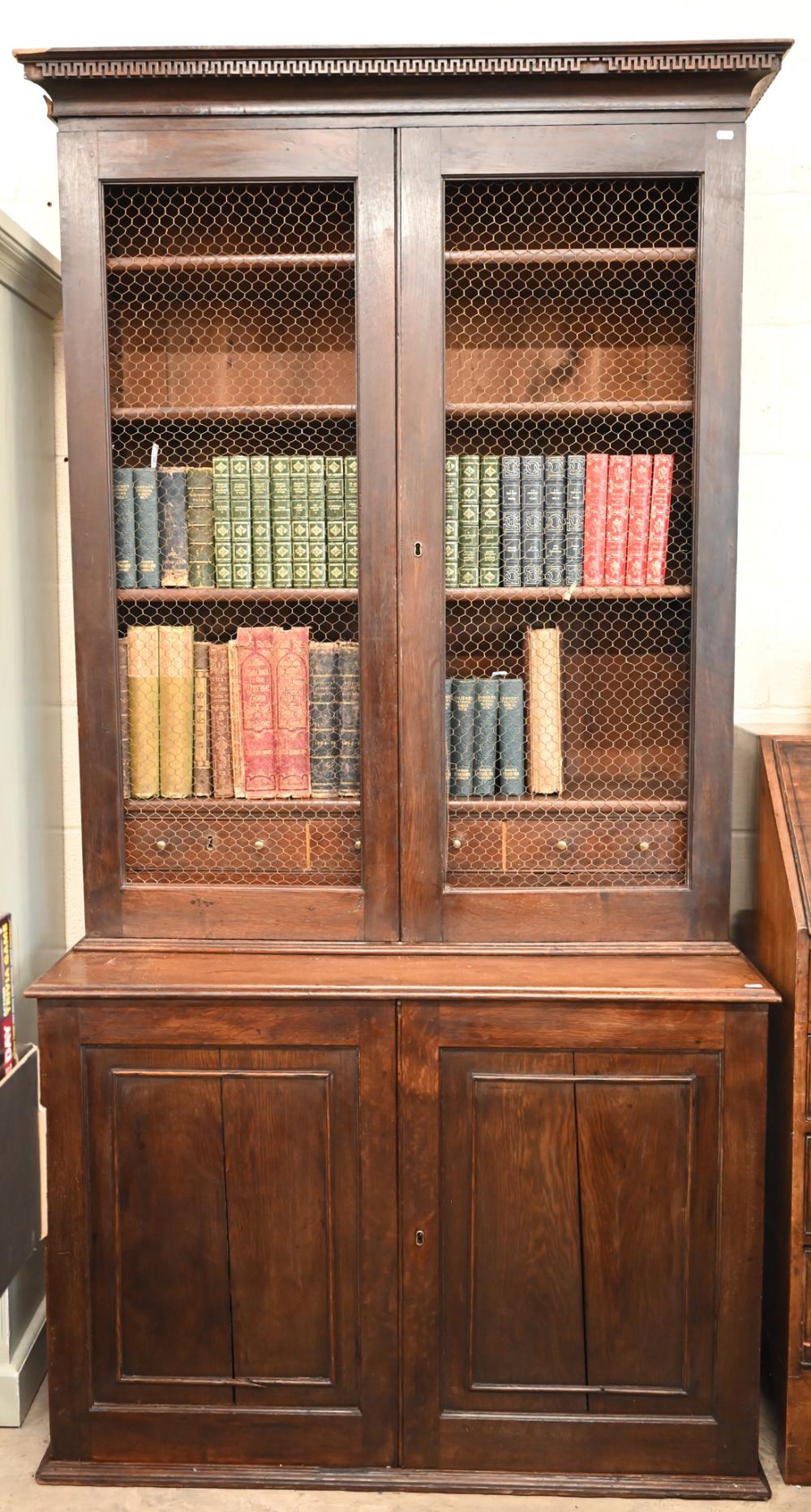 An antique oak cabinet bookcase, the lattice wire panelled doors enclosing shelves and small drawers