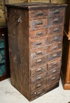 An antique stained pine twenty drawer chest, ex shop fitting, with cast metal fittings (one