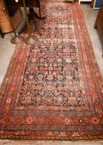 A North West Persian wide runner (very worn), with floral design on navy ground with red/blue