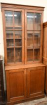 An early 20th century oak cabinet bookcase, the top section with glazed doors enclosing adjustable