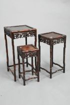 A nest of four antique Chinese rosewood tables, with carved and pierced side panels - the largest