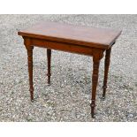 A late Victorian mahogany card table with baize-lined folding top and turned supports with brass
