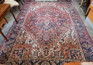 A vintage Persian Heriz carpet, the geometric design on red ground with navy border and large