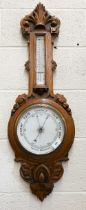 An early/mid 20th century carved oak wheel barometer with enamelled dials, 90 cm