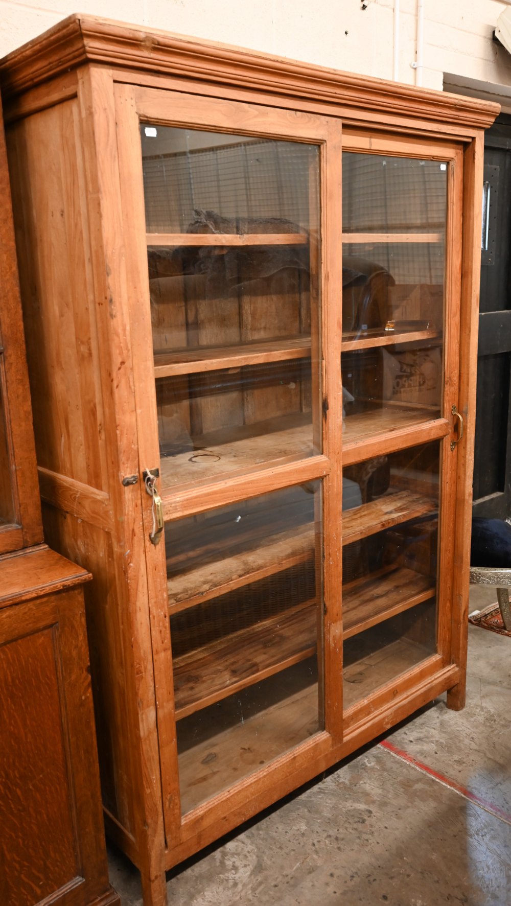 A stained hardwood bookcase with glazed sliding doors enclosing five shelves, 130 cm wide x 55 cm