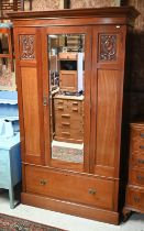 An Art Nouveau satin walnut wardrobe, the triple front centred by a mirrored door over a full