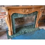 An ornate carved and moulded pine chimney piece, of serpentine form in the chateau style, with green