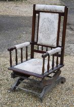 An Edwardian walnut framed rocking armchair with fabric panelled back and seat