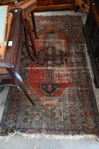 A North West Persian kavabagh rug, navy medallion on red ground with blue borders,181 x 118 cm to/