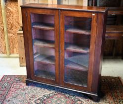 A mahogany twin glazed door bookcase raised on shaped bracket feet, 109 cm x 28 cm x 122 cm h