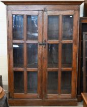 A rustic stained hardwood cabinet with glazed doors (one pane cracked), 120 cm wide x 50 cm deep x