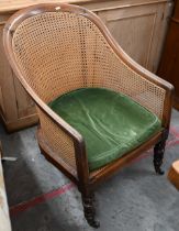 An antique mahogany framed bergere armchair, turned front supports and casters