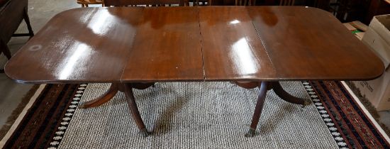 A Regency style mahogany extending dining table with three central leaves on twin pedestal