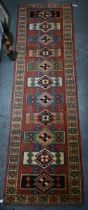 A Kazak design runner, the central medallions on a terracotta field, with geometric pattern and