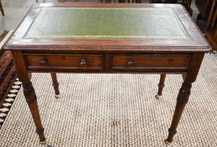 An oak two drawer writing table with tooled green leather top and turned supports on casters, 92