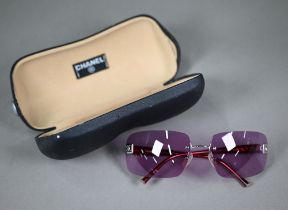 A cased pair of Chanel sunglasses with amethyst-shaded lenses