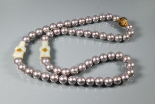 A row of uniform grey pearlescent beads with two Asian green hardstone figures between and yellow