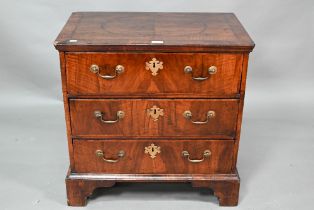 A small Georgian cross-banded mahogany chest of three long drawers, raised on shaped bracket, 68