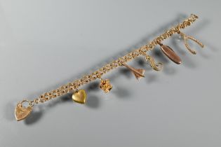 A 9ct yellow gold charm bracelet with padlock attached, and with seven various charms attached