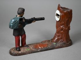 An antique novelty cold-painted iron money-box, cast as a soldier aiming at a tree