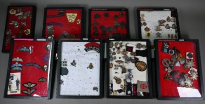 Eight perspex display cases of British military cap badges, shoulder titles, sweetheart brooches and