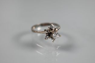 A diamond cluster ring in the form of a star, the central diamond in high claw setting above a