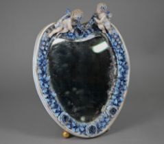 An antique Sitzendorf porcelain heart-shaped mirror surmouted by two cherubs, on floral-encrusted