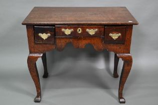 An 18th century oak three drawer side table with fret cut apron raised on four square cabriole legs,