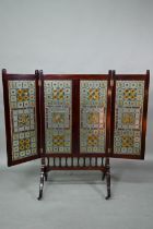 A good Arts & Crafts stained and leaded glass folding screen, the three folding walnut framed panels