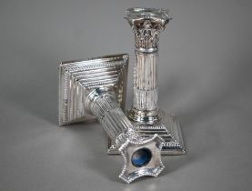 A pair of late Victorian loaded silver candlesticks with reeded and fluted classical columns on