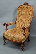 A Victorian walnut framed open armchair with carved crest, deep buttoned back and stuff-over