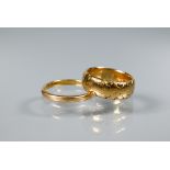 Two 18ct yellow gold wedding bands, one narrow size L, the other with rubbed decoration size H,