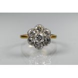 A diamond cluster ring in the form of a flower, millgrain set, stamped 18ct and plat, size P, approx